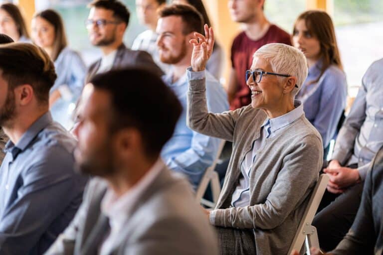 Senior raises her hand to ask a question at a seminar
