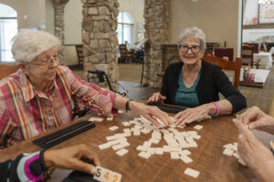 Two seniors playing a game at Tuscan Gardens Senior Living Community