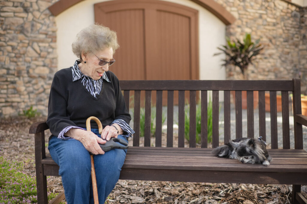  A Tuscan Gardens resident sitting on a bench with a Tuscan pet